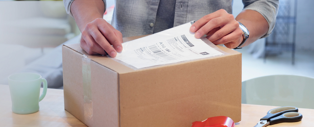 A man places a shipping label on a cardboard box.