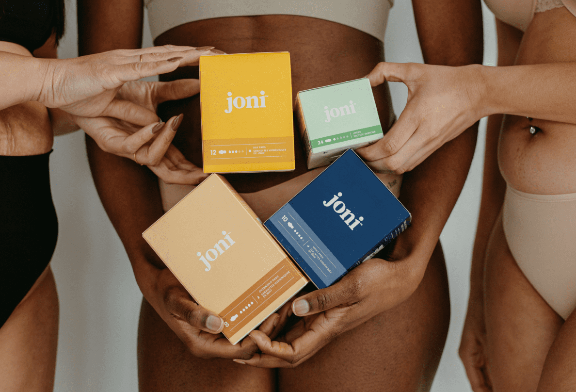 Three women wearing underwear hold colourful boxes of joni products.