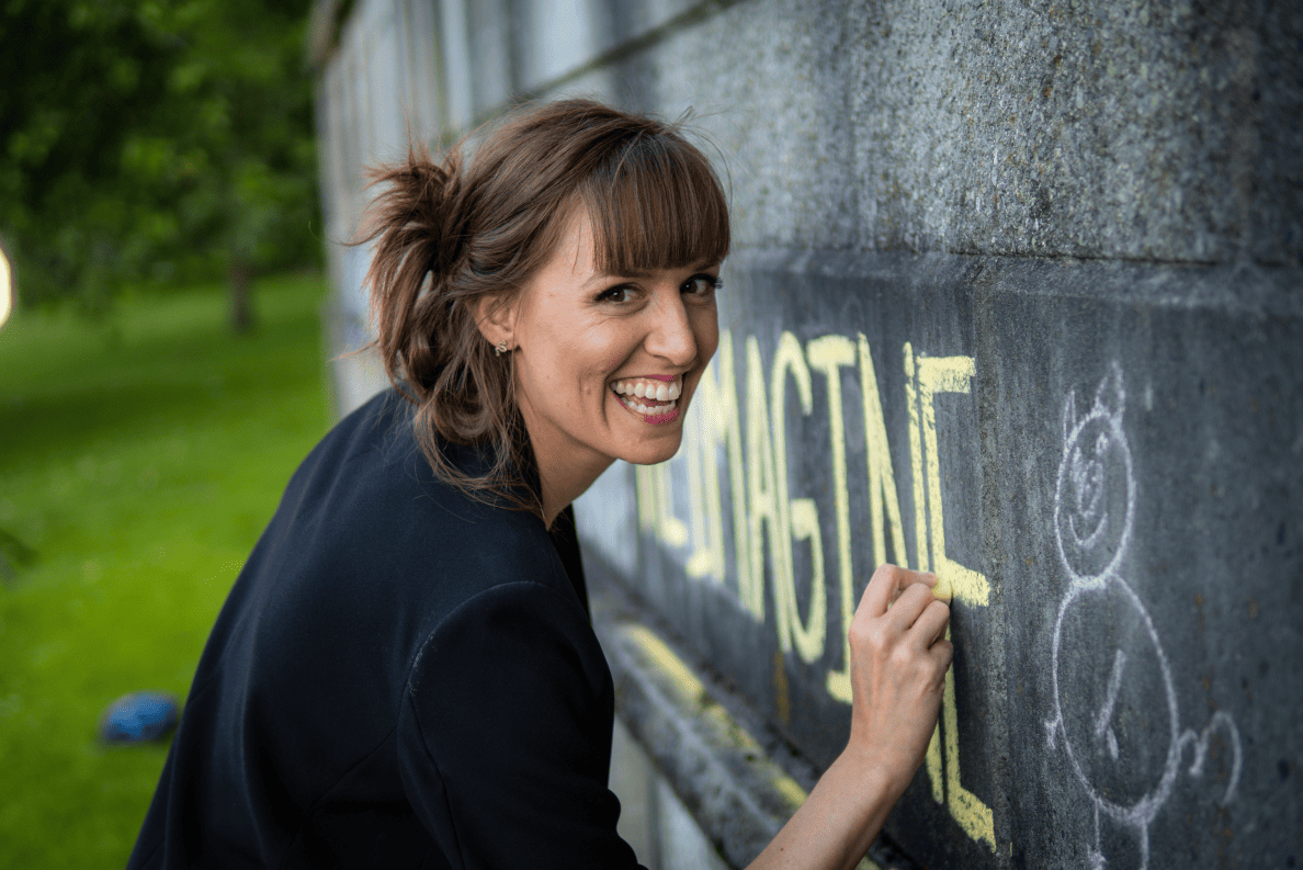 Futurist Lindsay Angelo writes “imagine” in yellow chalk on a wall and smiles