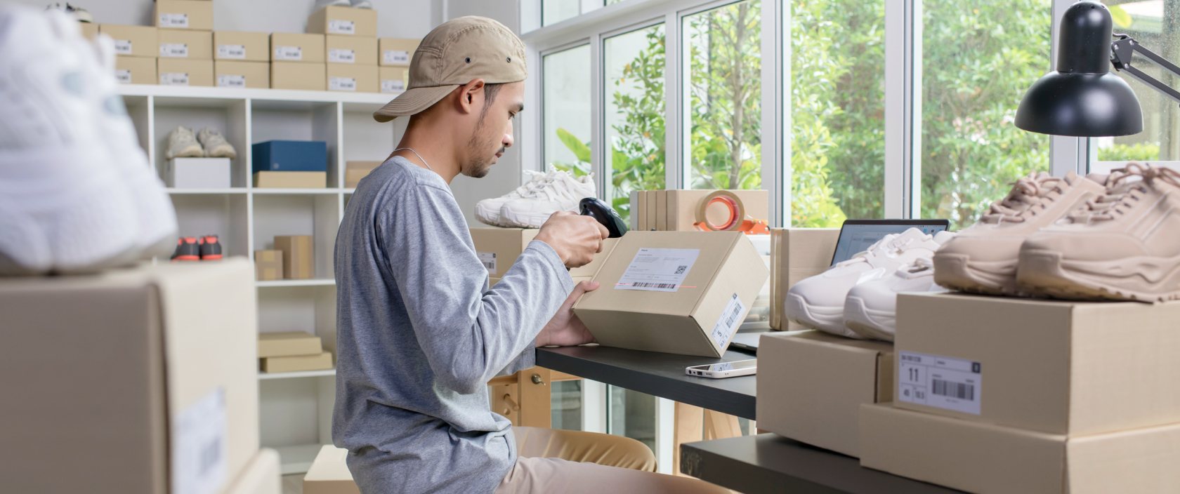 A young man scans a label on a shipping box in a room full of boxes.