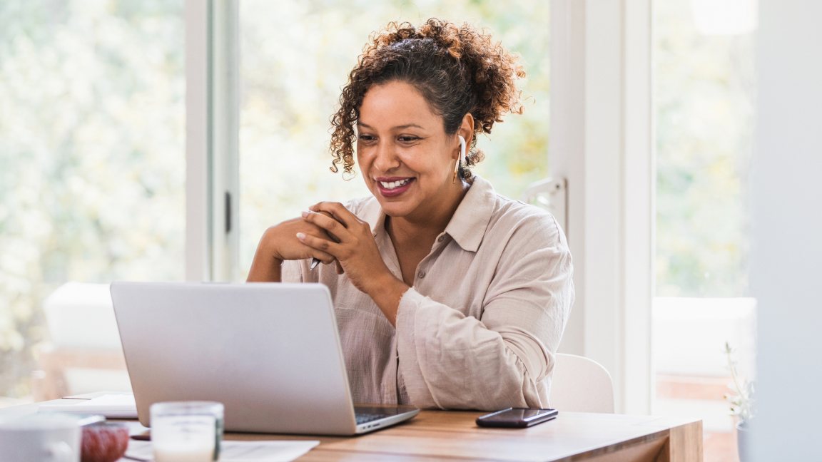 A woman sits in front of a laptop taking handwritten notes. A woman sits in front of a laptop taking handwritten notes.